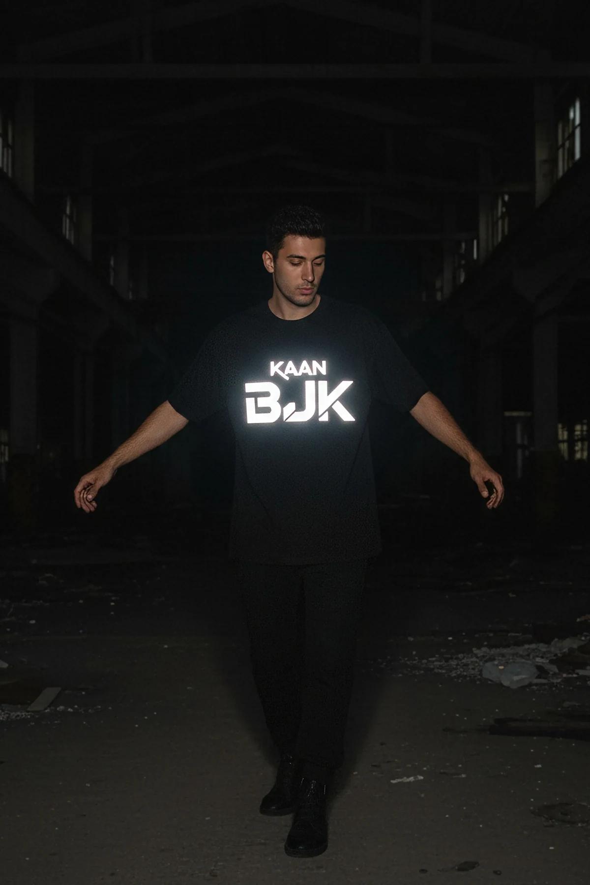 black oversized reflective logo t-shirt with glowing white chest graphic on male model in dark warehouse