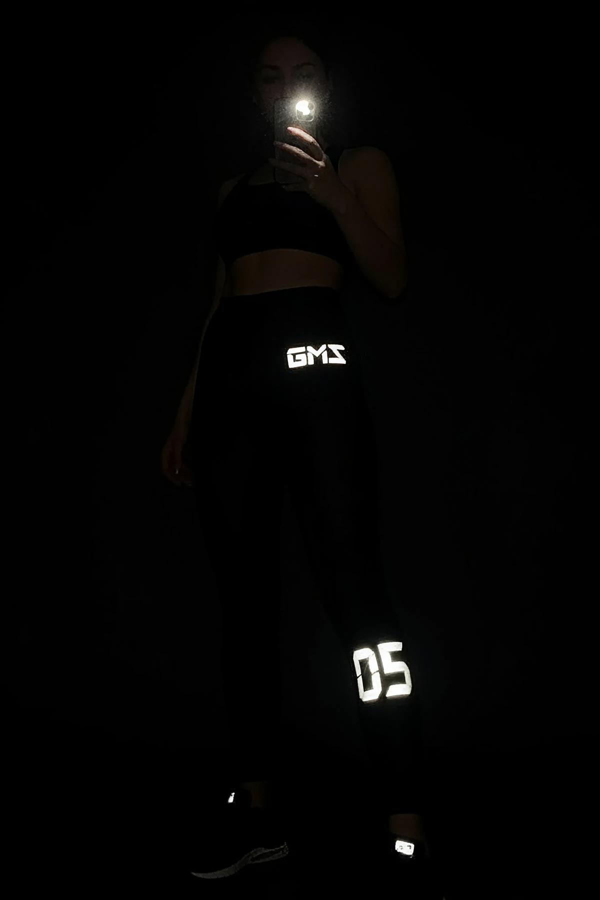 black high-waist performance leggings with white reflective letter print on outer thigh and calf full-length fit