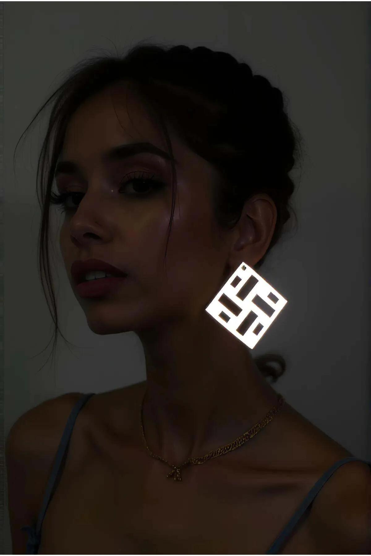 Beyaz reflektörlü lazer kesim kare küpe karanlık ortamda parlayan geometrik yüzey kulakta