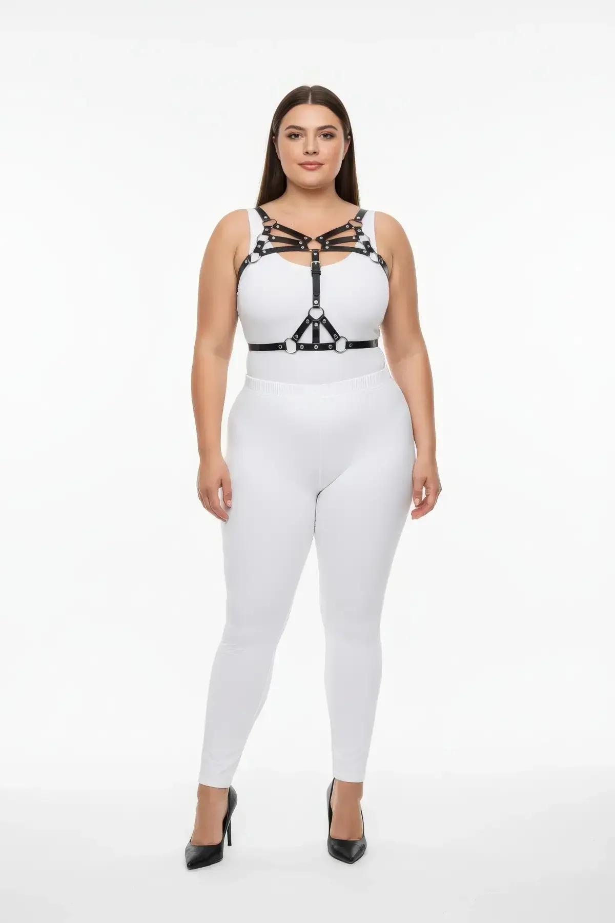 black faux leather strappy chest harness with silver O-rings worn over white bodysuit plus size model