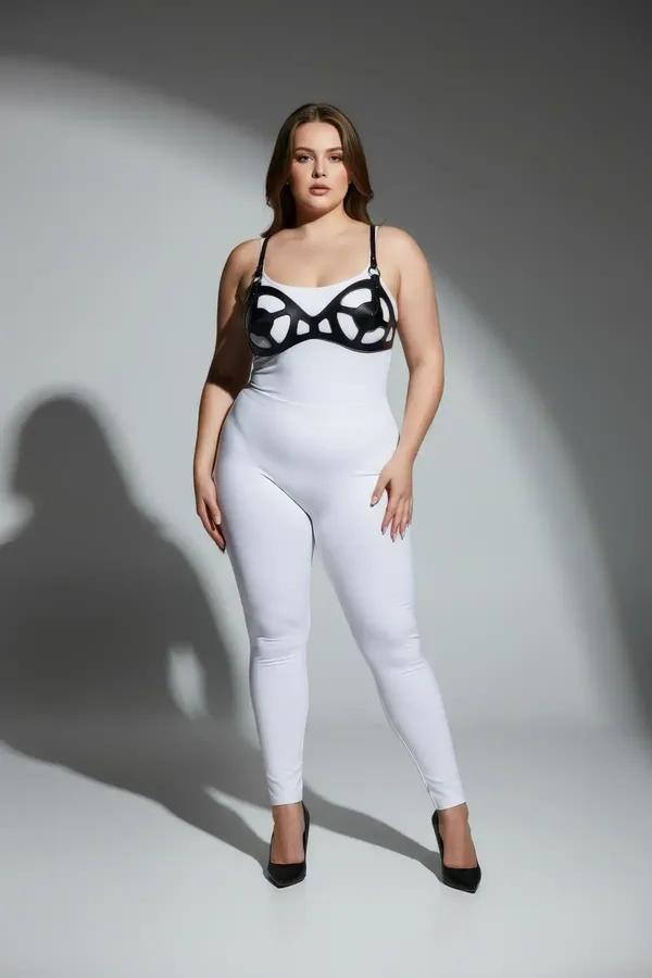 Black faux leather cage bra harness with curved organic cutout panels and silver hardware, worn over white bodysuit