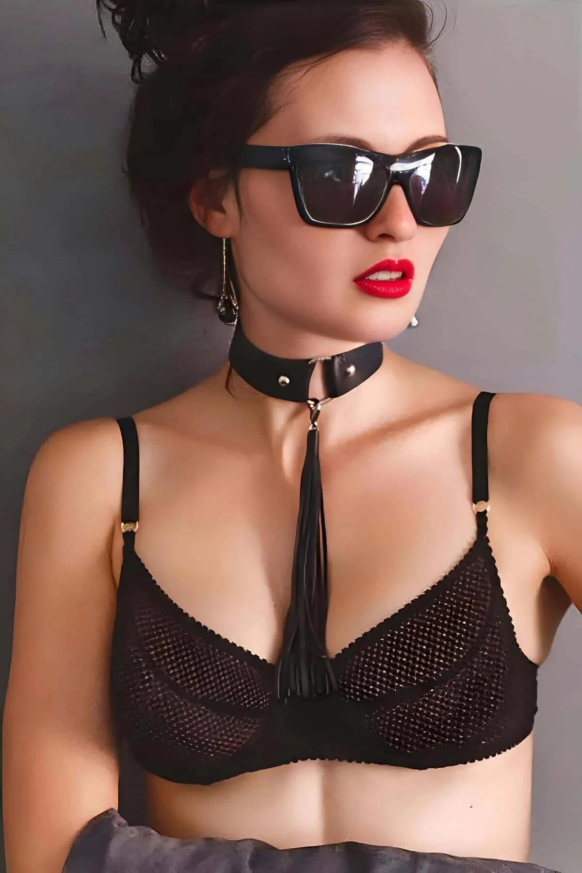 Black faux leather choker necklace with silver dome studs and detachable black tassel chain hanging from gold center ring