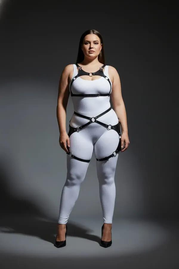 black faux leather full body harness with silver O-rings connecting chest waist and thigh straps worn over white bodysuit