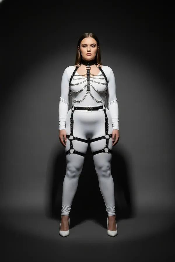 black faux leather full body harness with silver chain swags cage chest straps and thigh garter straps worn over white bodysu