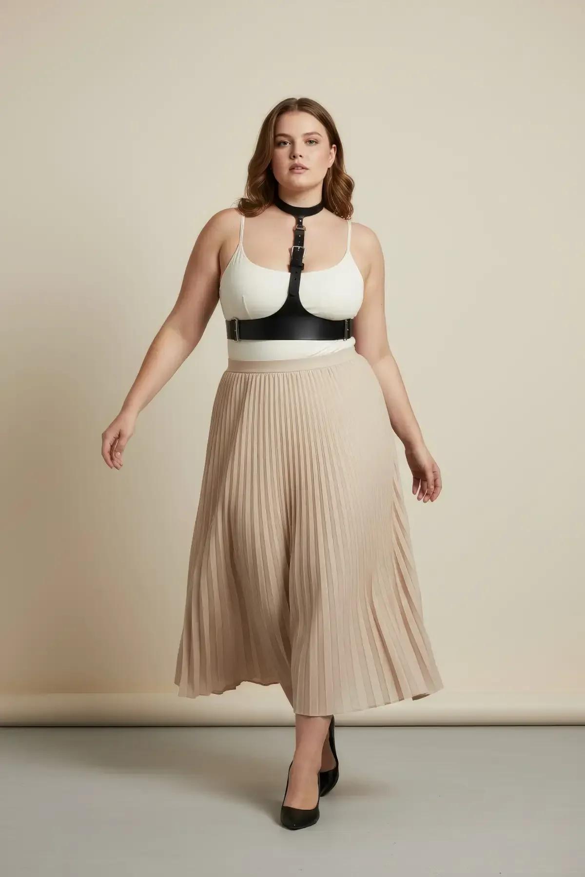 Black faux leather choker underbust harness with silver buckles worn over white bodysuit and beige pleated skirt