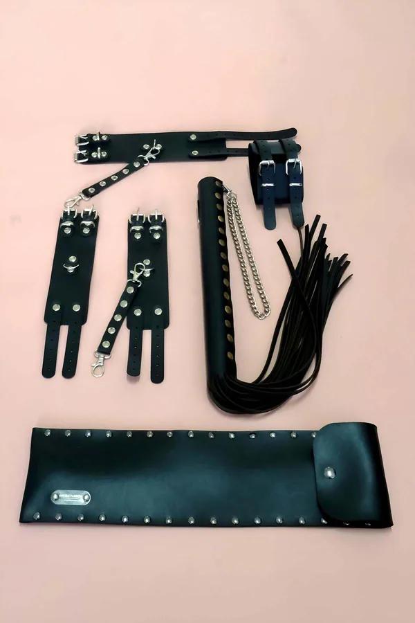 Black faux leather accessory set with two studded wrist cuffs, two mini bags, and a multi-strand tassel whip with silver chai