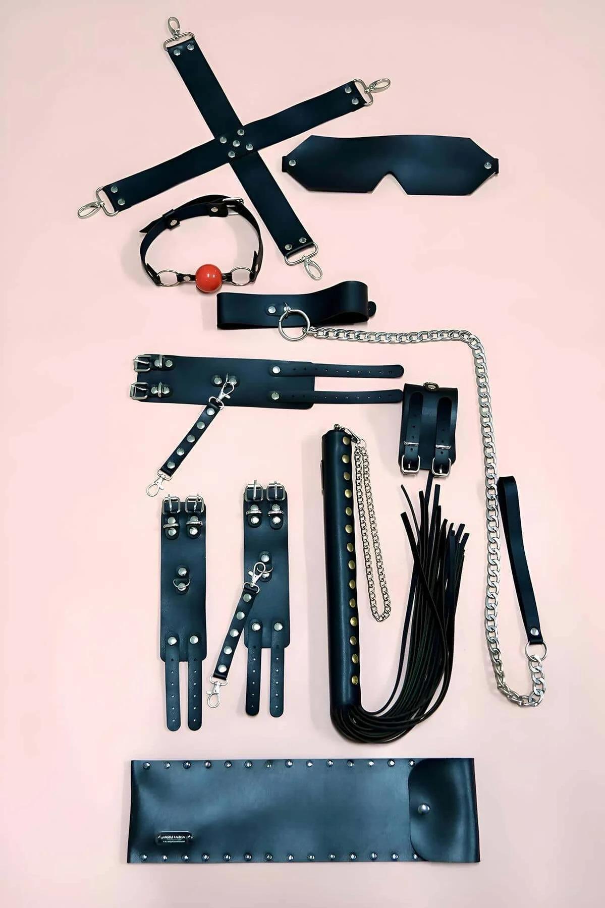 Black faux leather 7-piece restraint accessory set with hogtie bar, cuffs, eye mask, ball gag, collar chain leash, flogger, a