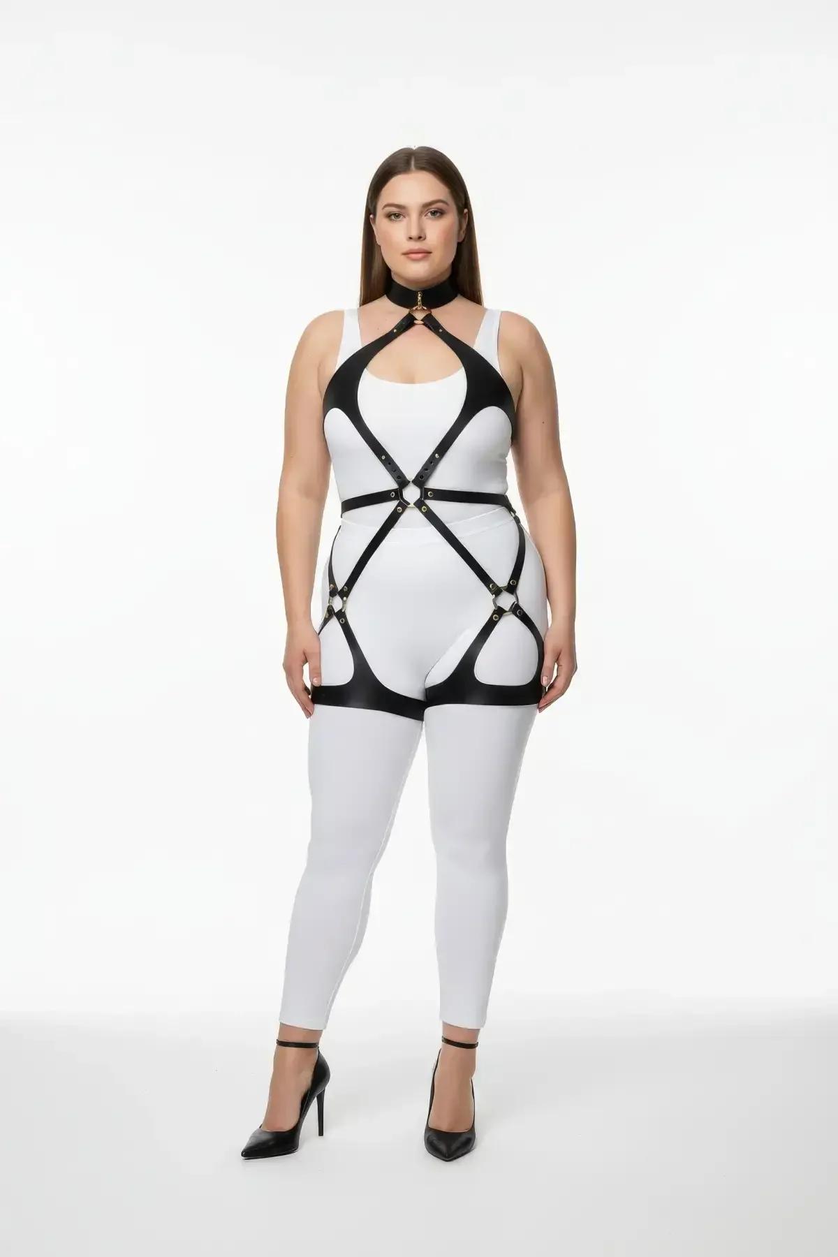 black vegan leather full body harness with neck collar, gold O-ring chest detail, and thigh straps worn over white bodysuit