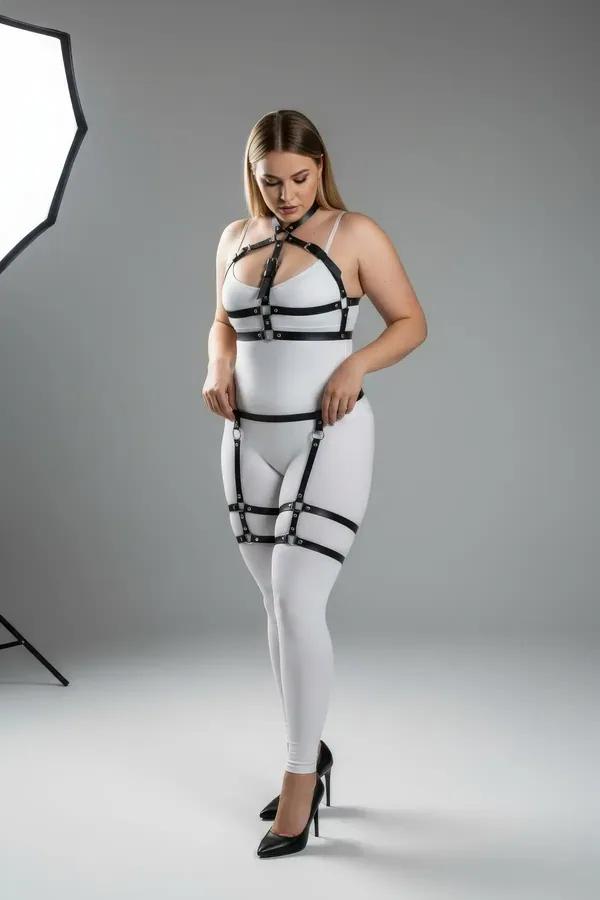 Black faux leather full body harness with garter straps, thigh bands, and silver O-ring hardware on plus-size model