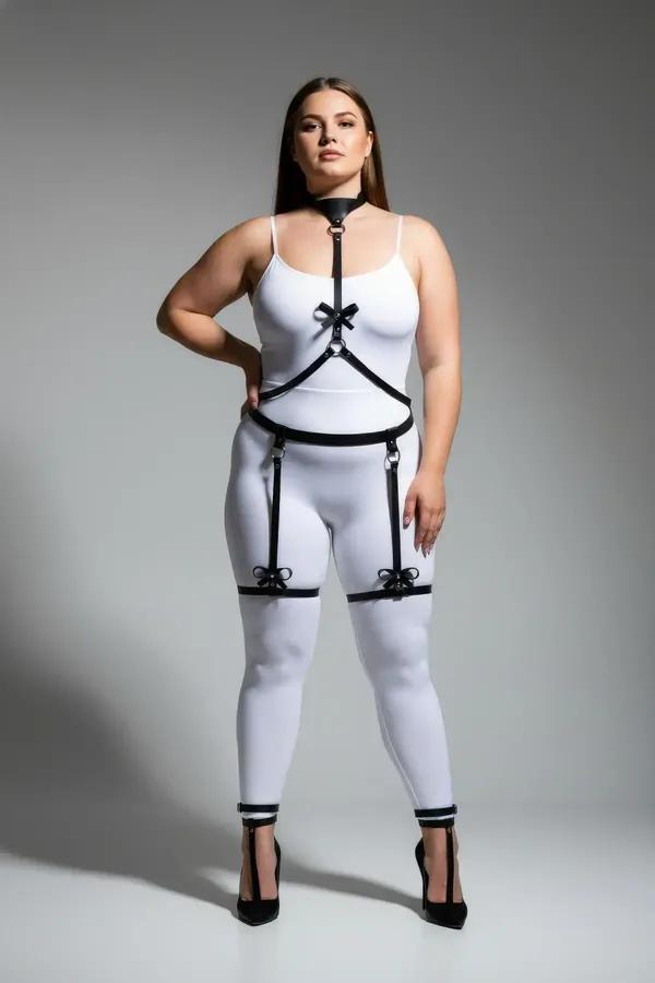 black faux leather body harness with bow garter straps and silver O-ring waist belt, worn on plus-size model