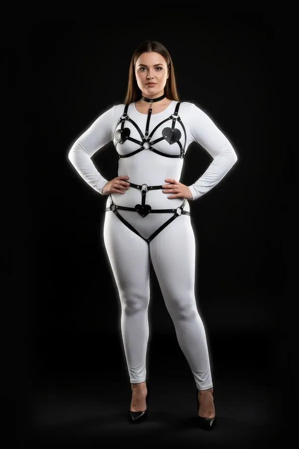 black faux leather harness bra and garter set with heart cut-out panels and silver O-rings on plus-size model