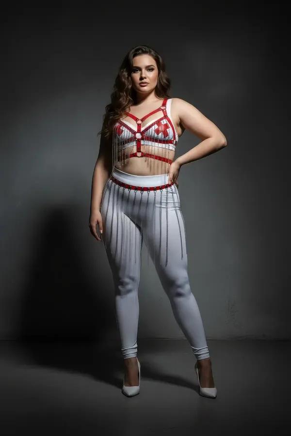White faux leather body harness set with red bust accent straps and silver chain fringe skirt belt worn over white leggings