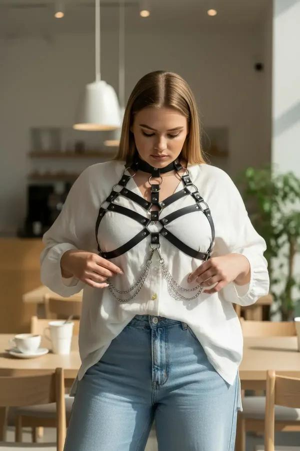 black faux leather o-ring chest harness with layered silver chains and choker collar worn over white dress