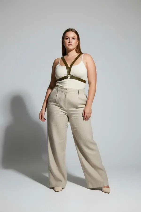 olive green faux leather o-ring chest harness with gold-tone hardware worn over white tank top plus size model