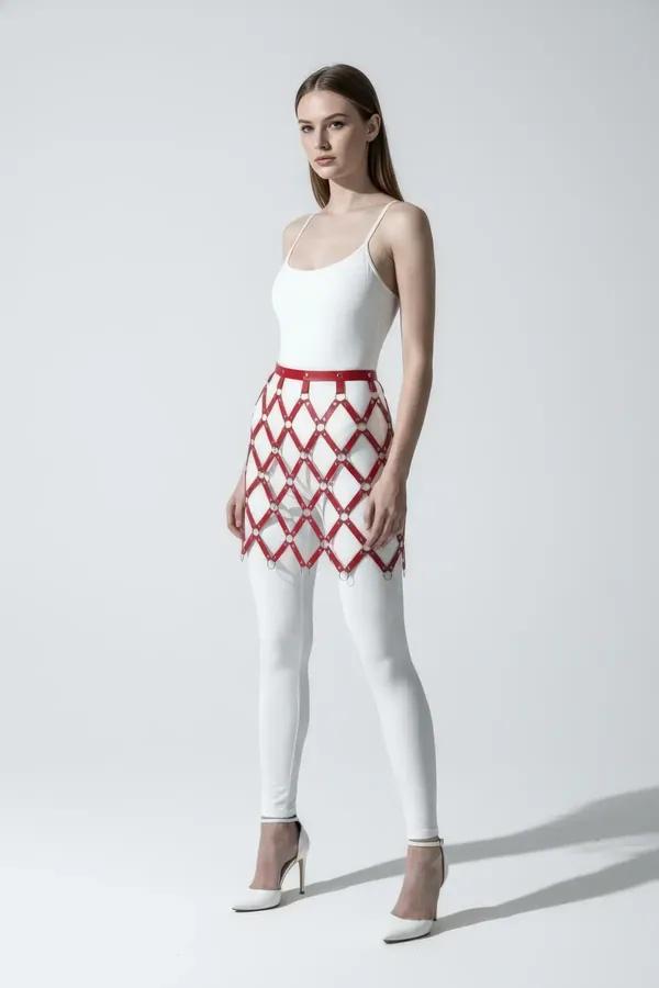 Kırmızı suni deri baklava desenli mini harness etek gümüş O-halka detayı, beyaz tayt üzerine giyilmiş