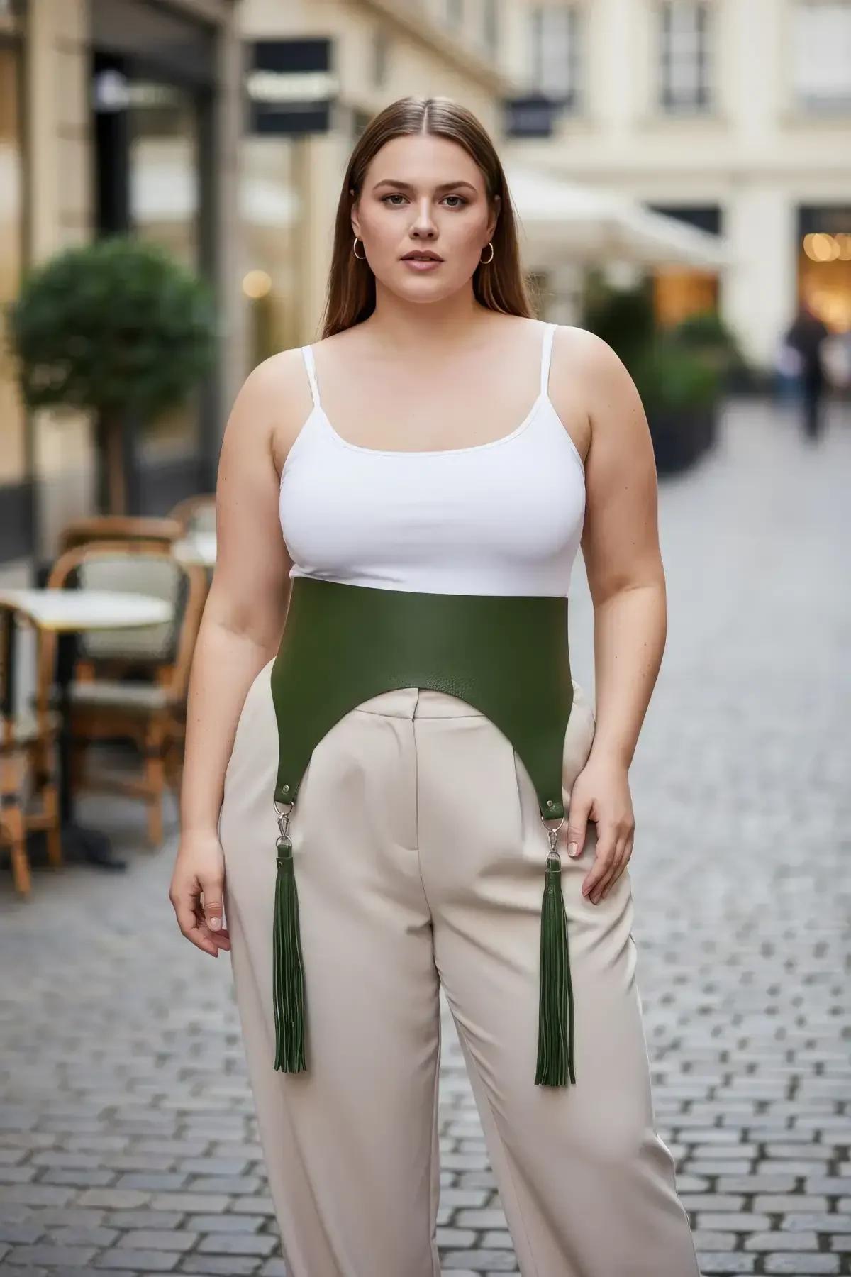 olive green wide faux leather waist harness with detachable tassels and silver clip hardware worn over white tank and beige t
