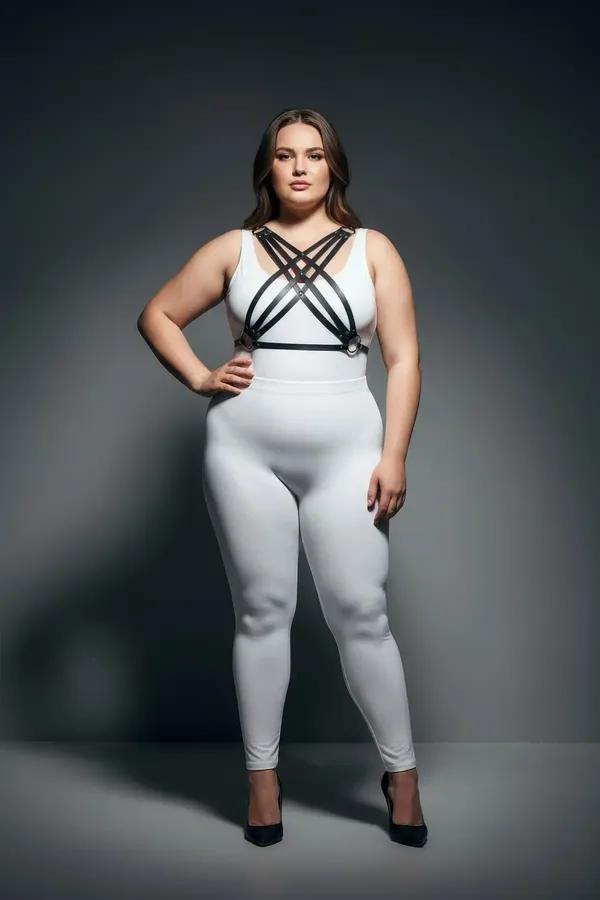 black faux leather chest harness with four crisscross diagonal straps and silver-tone studs worn over white outfit