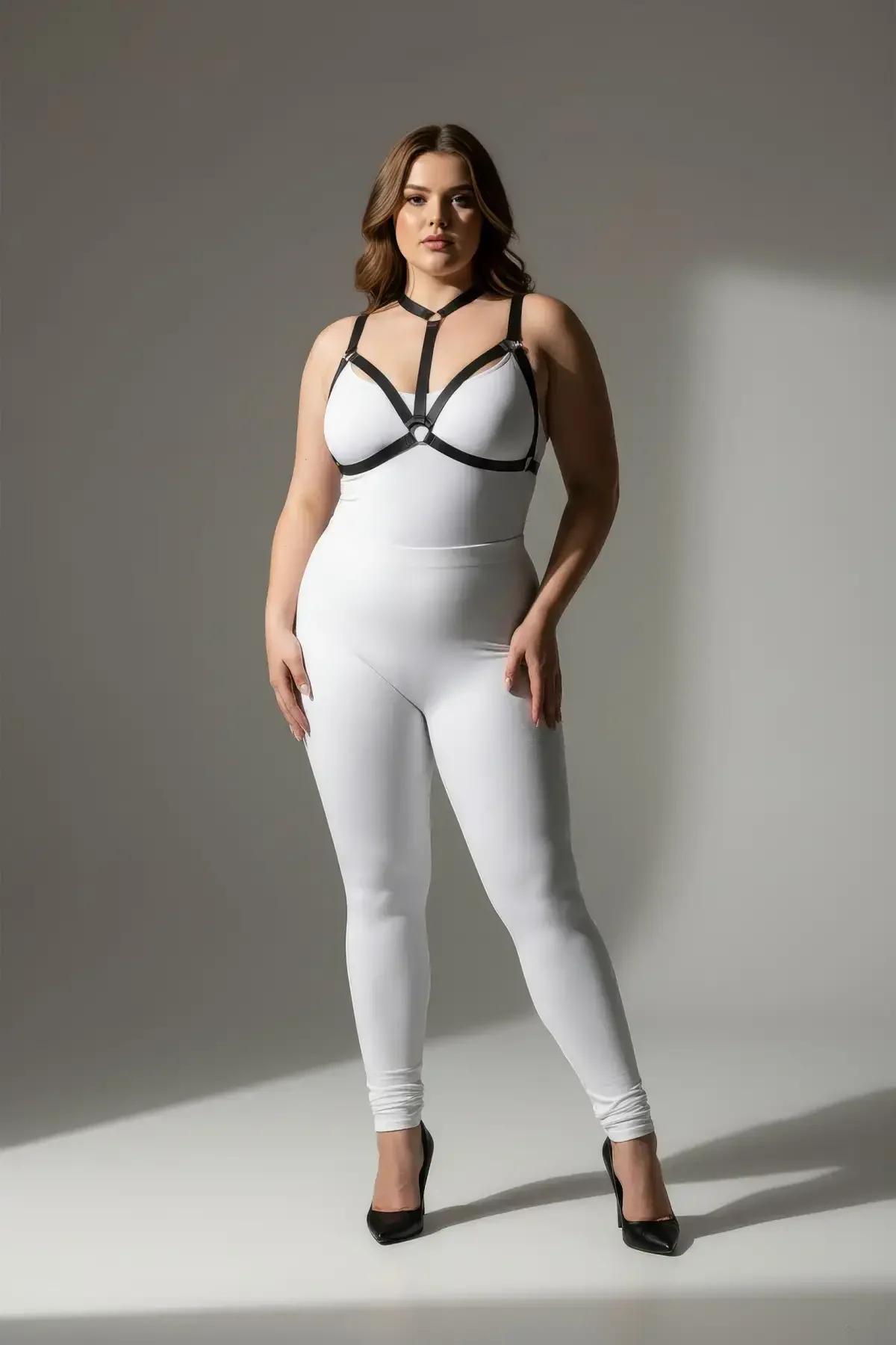 black faux leather strappy O-ring body harness with silver hardware worn over white bodysuit