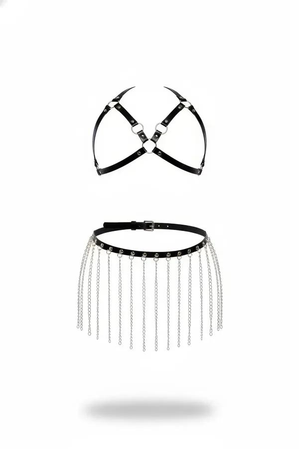 Black faux leather chest harness with silver O-rings and matching chain fringe belt skirt set, flat lay on white background