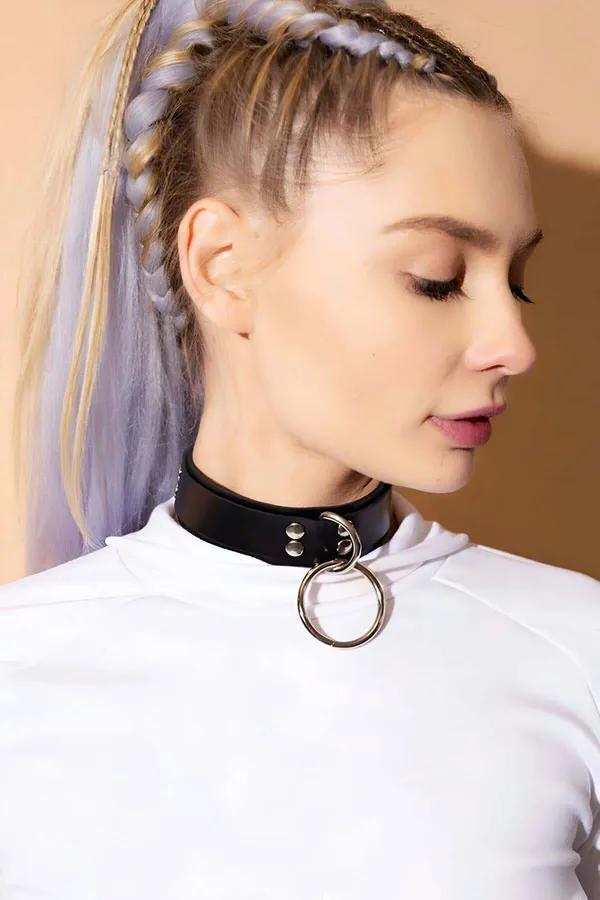 black faux leather O-ring choker with silver studs worn at throat over white mock-neck top