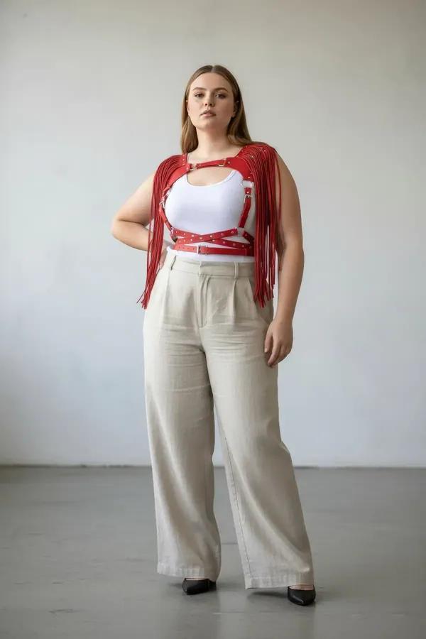 red faux leather fringe body harness with silver studded straps and O-rings worn over cream crop top