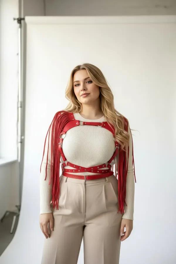 red faux leather fringe body harness with silver studded straps and O-rings worn over cream crop top