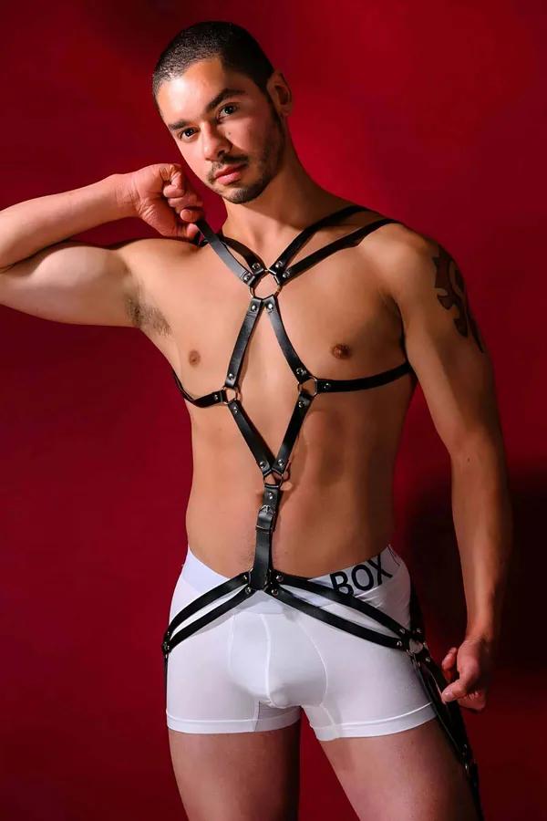 Black faux leather strappy body harness with silver O-ring accents and rivet hardware, chest to hip, worn by male model
