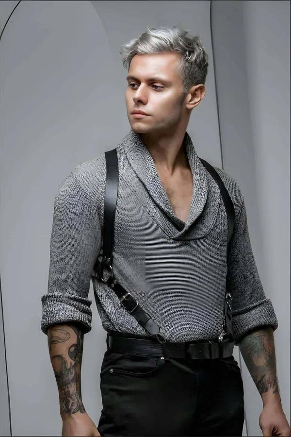 black faux leather mens chest harness X-cross strap design with dark metal buckle clasps worn over grey knit sweater