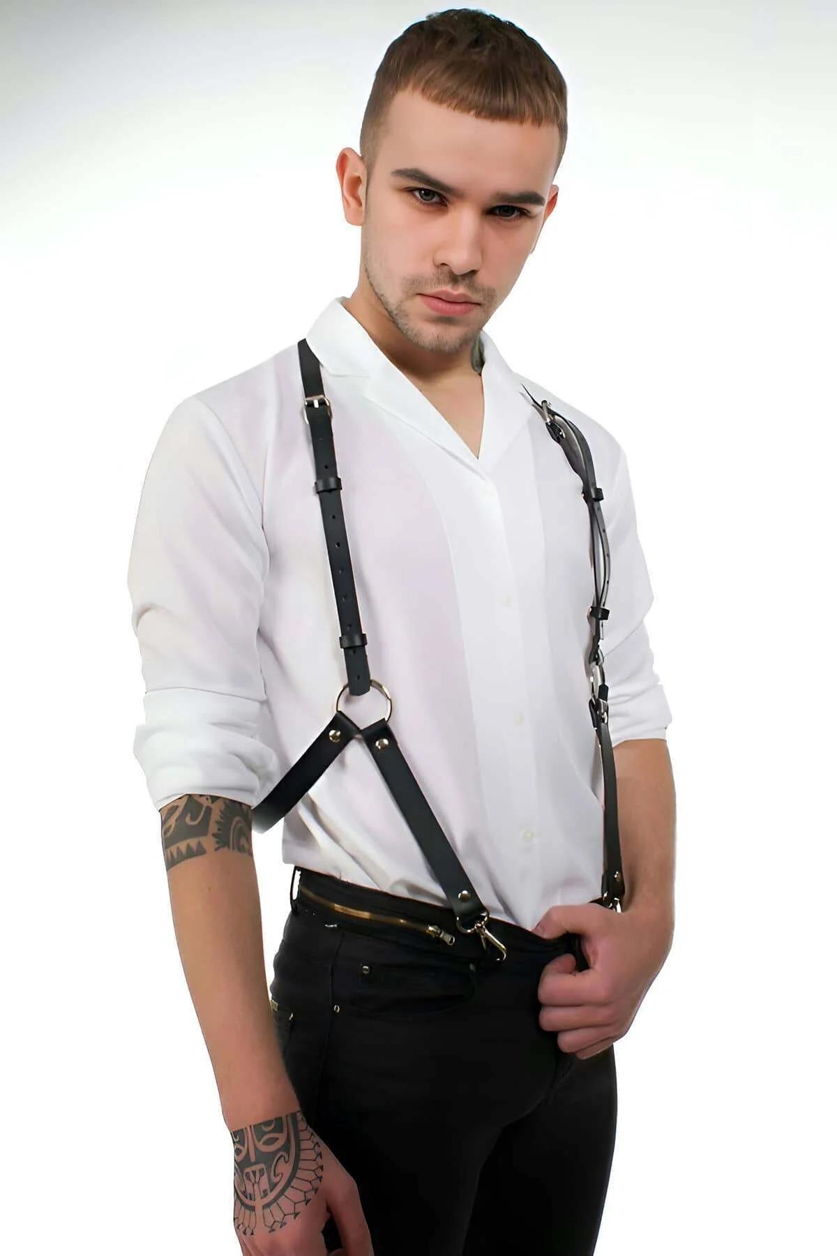 Black faux leather men's body harness with silver O-ring chest detail and trouser clips worn over white shirt