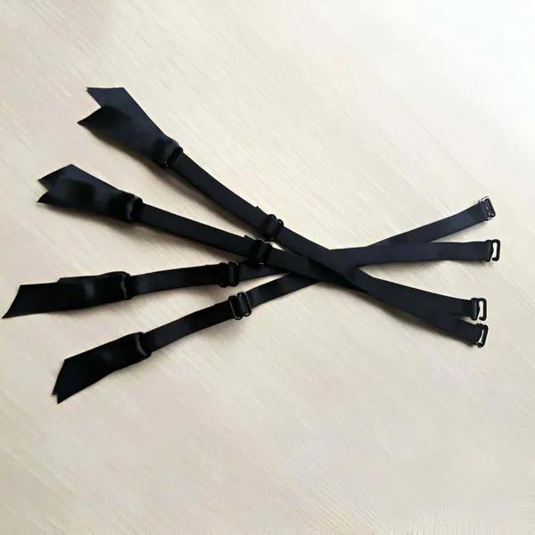 black adjustable elastic garter straps 4 pack with matte metal clip hooks laid flat on light surface