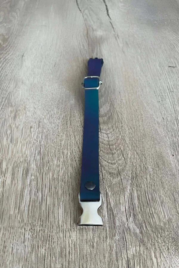 Blue reflective adjustable cat collar with silver metal quick-release buckle laid flat on wood surface