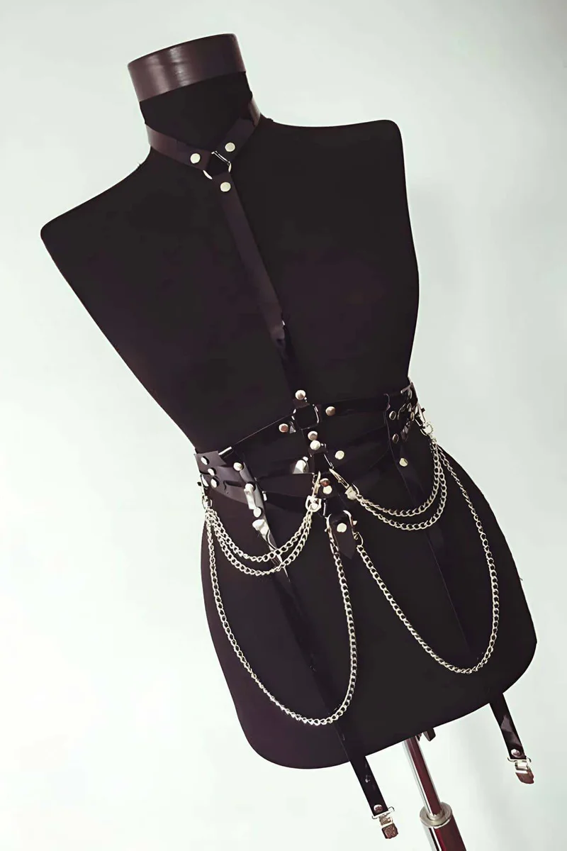Full body shot of faux leather chest harness with chains and garters visible