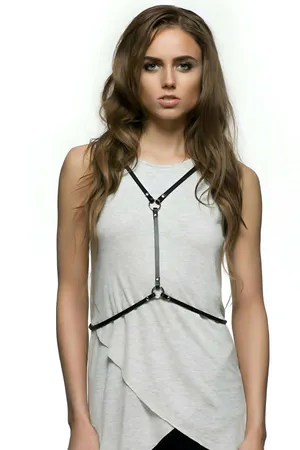 Black faux leather X-back body harness with O-ring detail worn over a white tank top