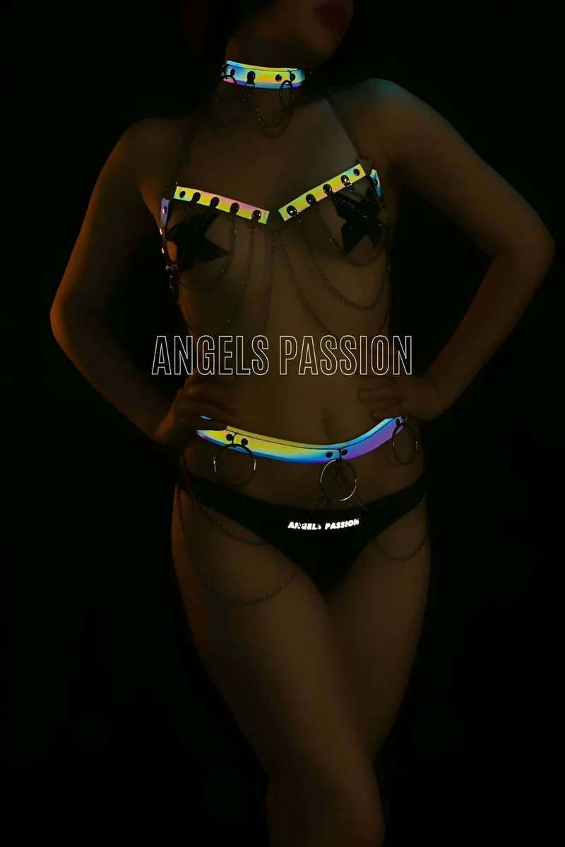 Model wearing reflective choker and body harness with chain details and black underwear