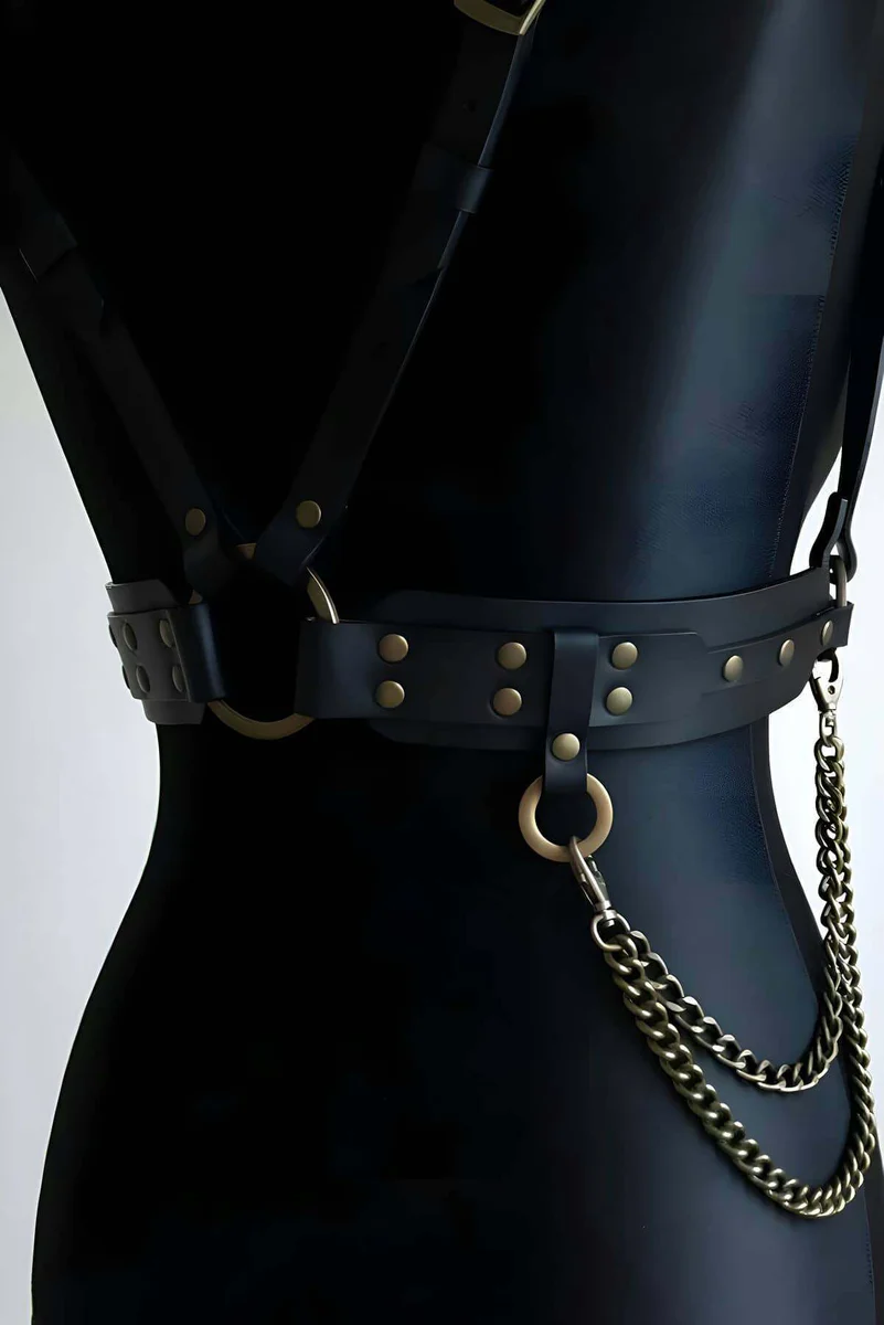 Black faux leather body harness front view with O-ring detail and chain accents.