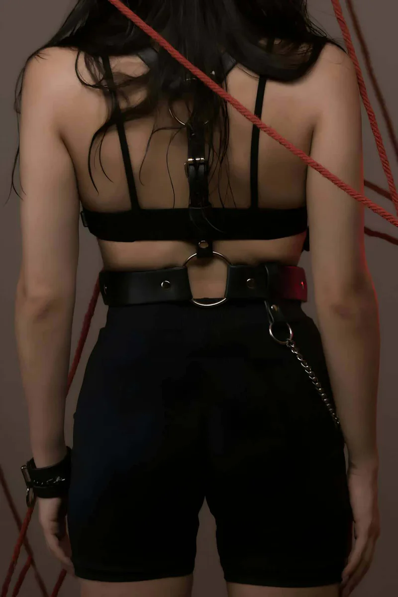 Close-up of O-ring and buckle hardware on black faux leather body harness