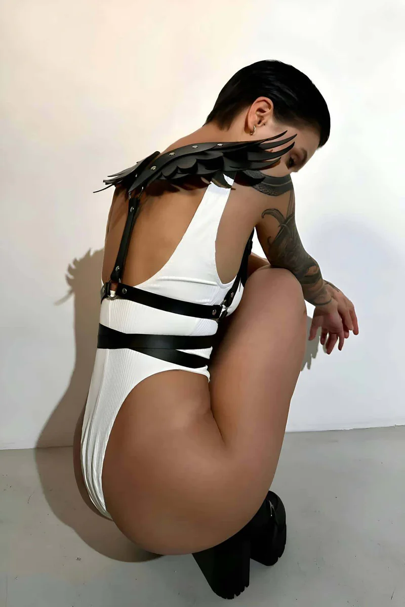 Side view of black faux leather body harness with adjustable straps and wing accents