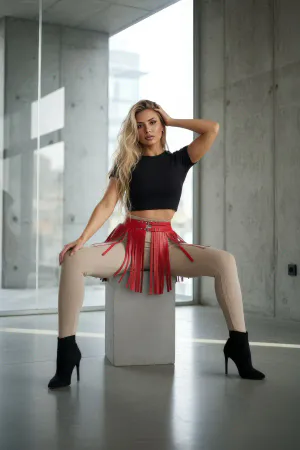 Kırmızı suni deri kısa etek modeli, bel kısmında metal toka ve bol hareketli püsküller ile kombinlenmiş