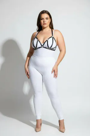 Black faux leather strappy chest harness with silver O-ring hardware, worn by a plus-size model.