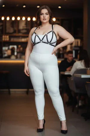 Black faux leather strappy chest harness with silver O-ring hardware, worn by a plus-size model.