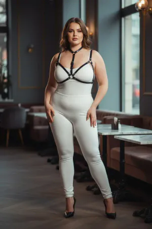 Black faux leather strappy body harness worn by a plus-size model, showing adjustable straps and O-ring detail.