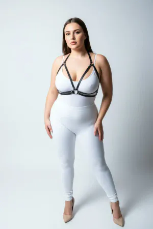 Black minimalist faux leather chest harness with central O-ring and adjustable straps worn by a plus-size model.