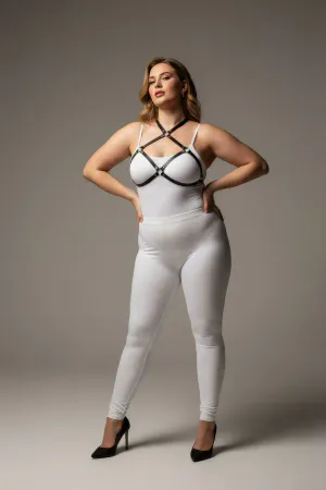 Black faux leather strappy chest harness with O-ring details, worn by a plus-size model.