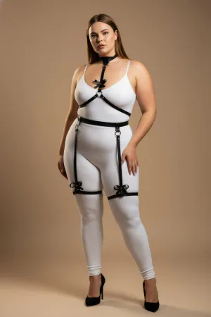 Black vegan leather body harness with choker, chest straps, O-rings, and decorative bow garter straps.